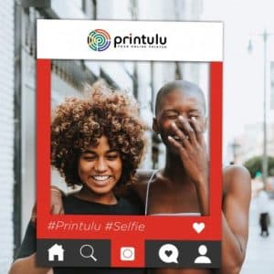 Two women smiling with a Printulu selfie frame