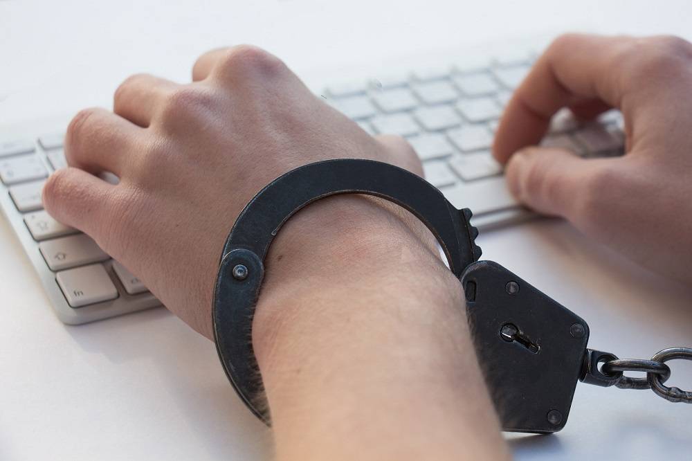 person typing on keyboard in shackles